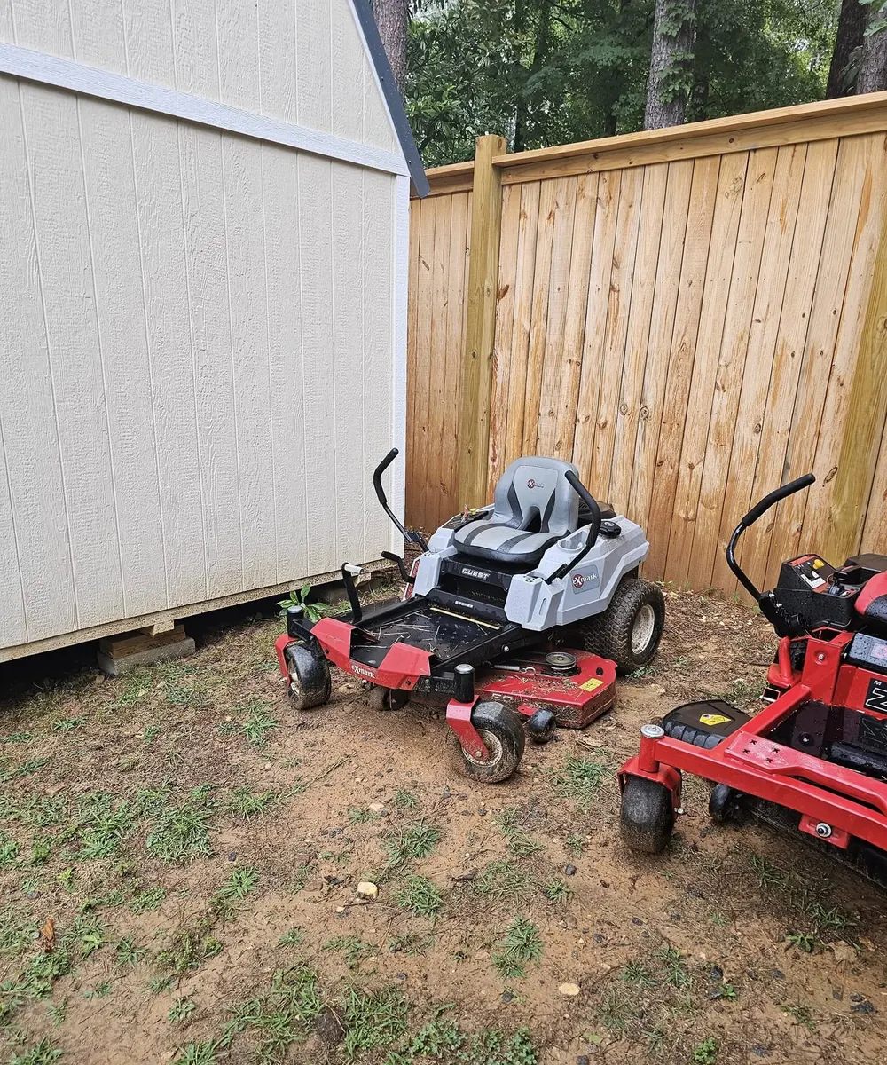 Zero-turn mower staged beside a fence for yard maintenance